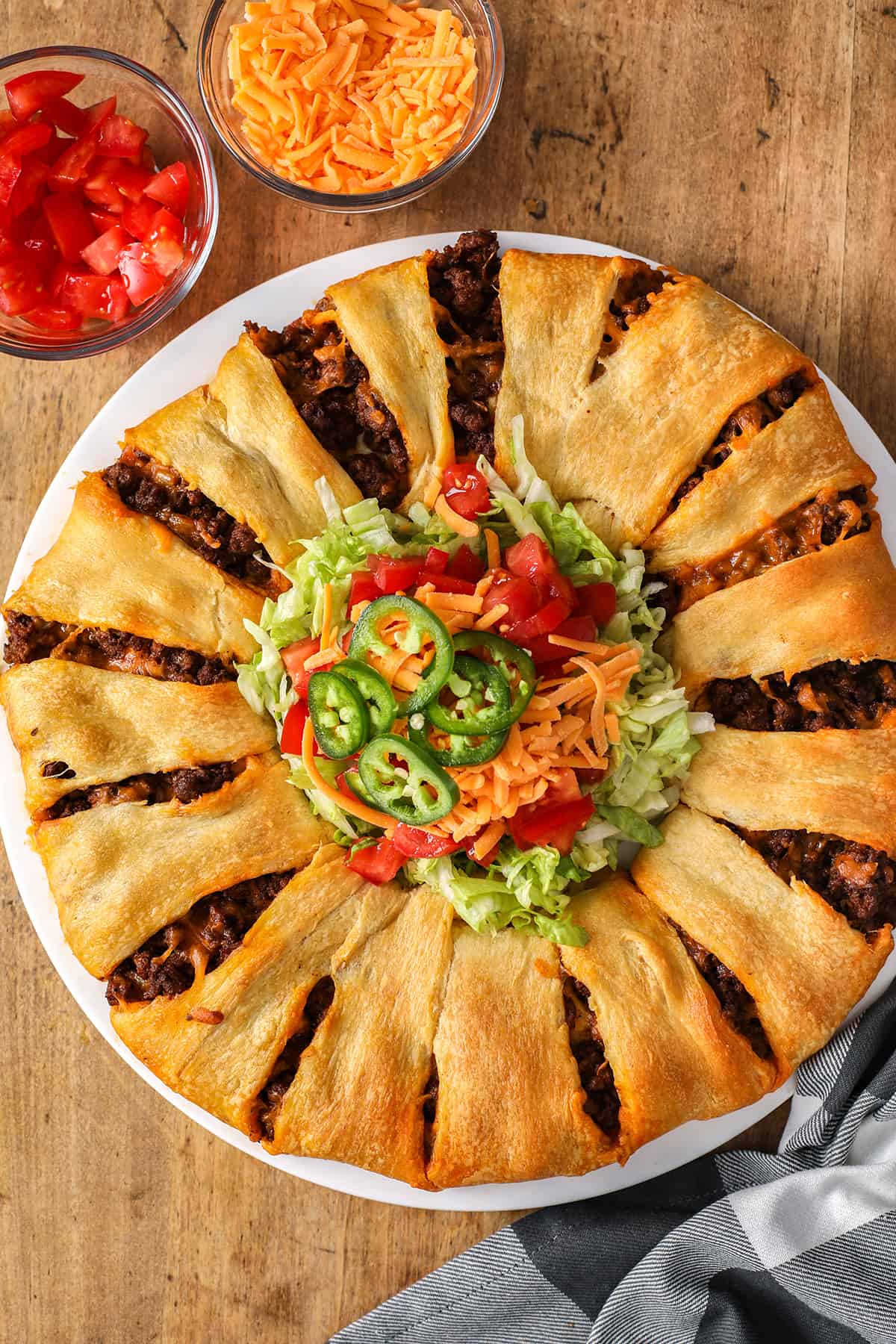 This taco ring recipe is a great party appetizer! It is easy to prepare with a handful of ingredients, like beef, crescent rolls, and seasonings, and is absolutely delicious. It's the perfect appetizer for a crowd, set out the toppings in bowls and let everyone choose their faves! #tacoring #tacocrescentring #appetizer #spendwithpennies cooked Taco Ring with toppings