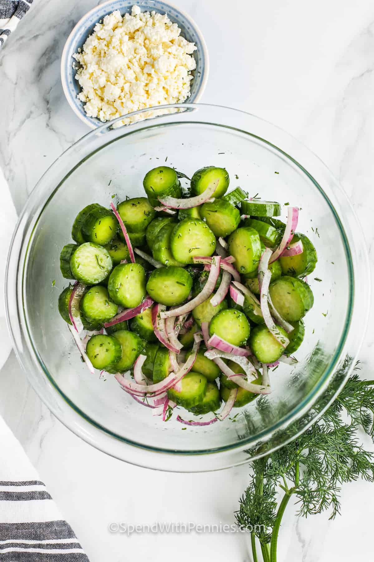 Zesty cucumber feta salad is full of fresh flavors and crunch. Fresh cucumber slices are combined with red onions, feta cheese, and savory herbs and tossed in a tangy lemon vinaigrette. Vary the ingredients by adding other vegetables like radishes, cherry tomatoes, or avocado. Kalamata olives and mint will give it a Greek flair. #cucumberfetasalad #cucumberfetasaladrecipes #cucumbersaladvinegar #spendwithpennies mixed ingredients to make Cucumber Feta Salad