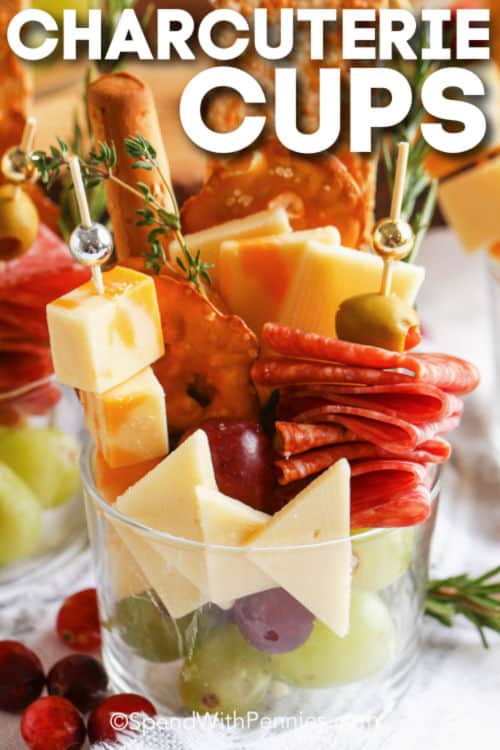 Charcuterie cups are a fave with kids because they’re filled with colorful ingredients, they’re easy to carry, and mess-free! Add some lids to match and these can turn into the ideal take-along snack. Wondering what to put in individual charcuterie cups? It's easy, just layer with colorful and tasty ingredients like meat, cheese, veggies, or fruit. There are so many ideas! #charcuteriecups #charcuteriecup #individualcharcuteriecups #spendwithpennies close up of individual Charcuterie Cups with a title