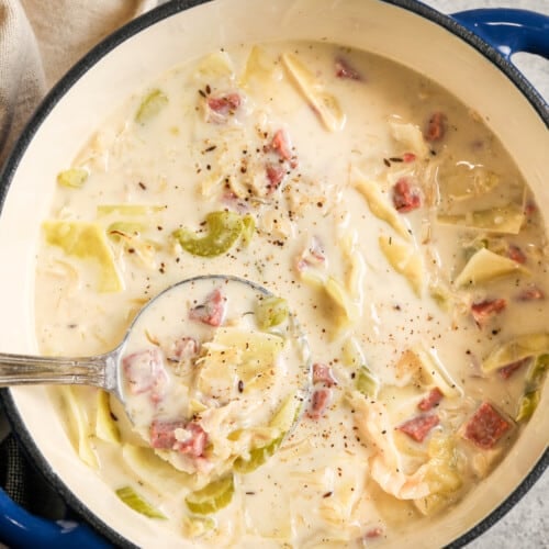 a pot of reuben soup with a ladle in it next to pickles