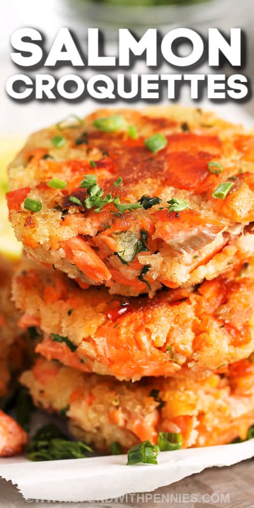 Salmon Croquettes are a fun twist on the original salmon fillet! Salmon, mayo, panko, lemon juice and chives mixed with herbs, then shaped into patties and baked until perfectly crispy! #salmoncroquettes #baked #easy #salmon #spendwithpennies stack of Salmon Croquettes with a title