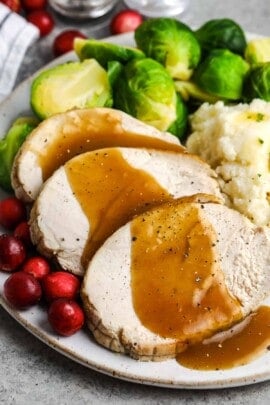 roast turkey breast on a plate with gravy and sides