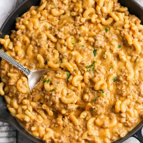 A skillet of cheeseburger macaroni with a spoon