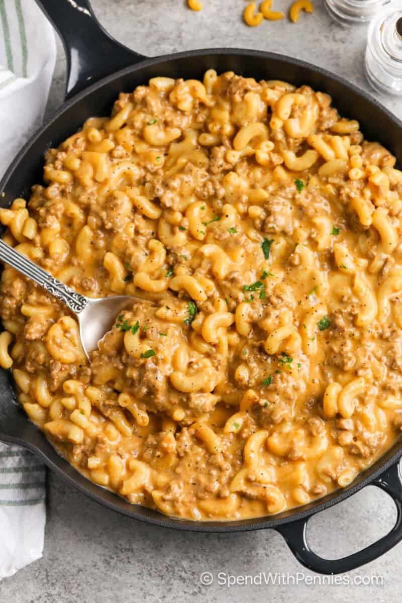 A skillet of cheeseburger macaroni with a spoon