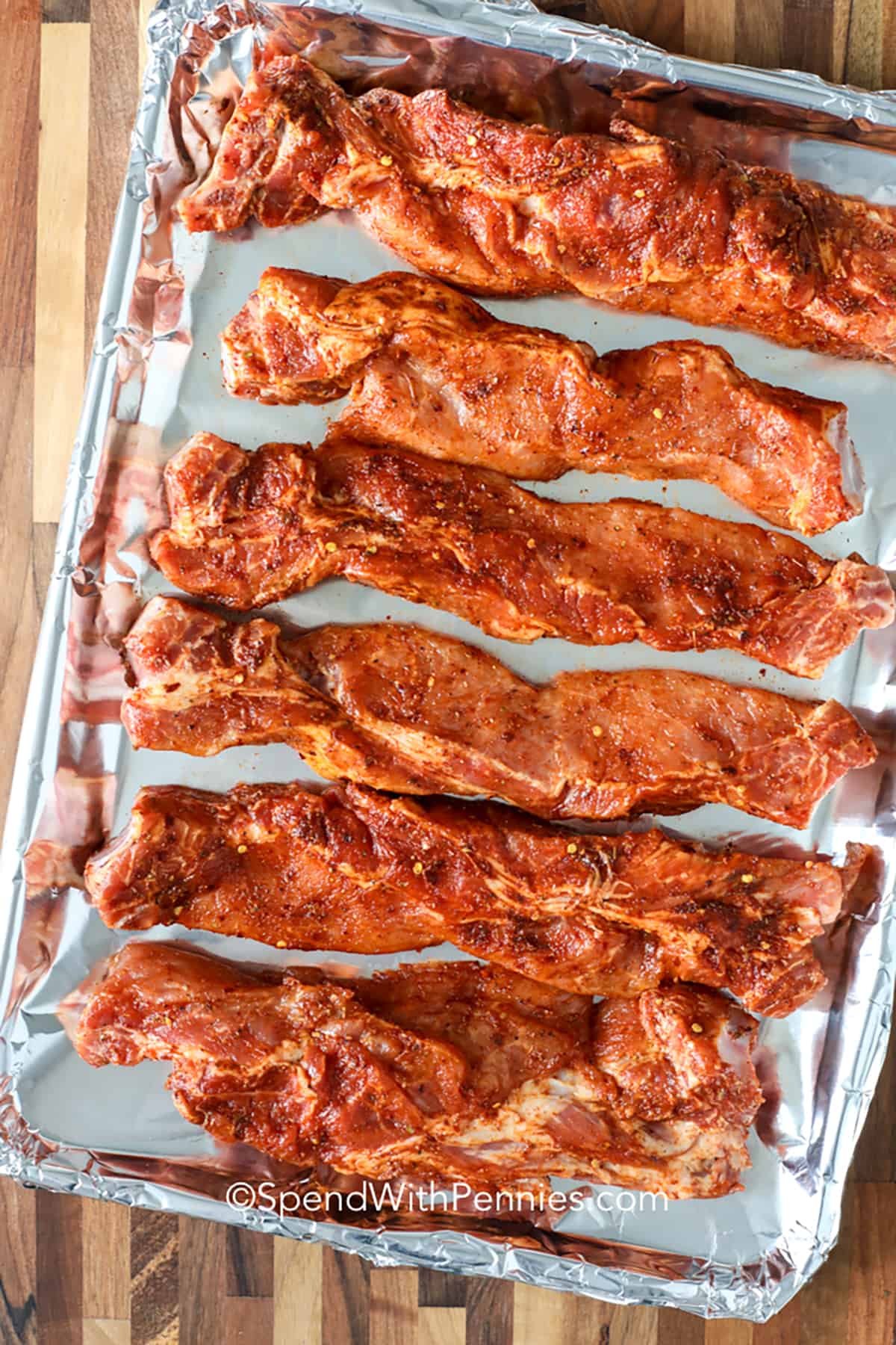 Country style ribs are the ultimate comfort food, perfect for any occasion! These ribs are seasoned with a flavorful homemade rub, slow-cooked until tender, and finished with a generous brushing of barbecue sauce. The result is a dish that’s rich, smoky, and absolutely delicious. Whether you’re cooking for a crowd or just a cozy night in, these ribs are sure to be a hit. Pair with your favorite sides for a meal everyone will love! #spendwithpennies seasoned ribs on a sheet pan to make BBQ Country Style Ribs