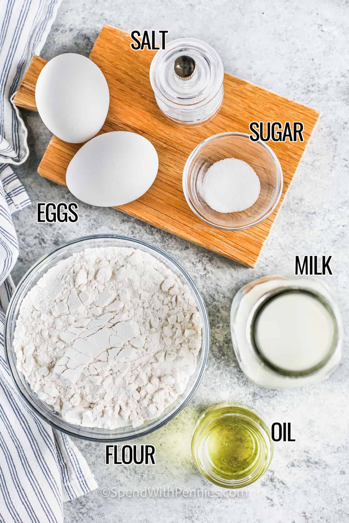 This crepes recipe is super versatile. These can be filled with anything sweet or savory, or nothing at all! They come out perfect every time. Crepes are a popular French treat and resemble a very thin pancake. The batter is much thinner. They are served everywhere from street food stalls to fine dining restaurants. This easy crepe recipe is always a favorite and will be made again and again. #crepesrecipe #simplecrepesrecipe #bestsimplerecipe #spendwithpennies Salt, sugar, eggs, milk, oil and flour with labels for an easy crepes recipe