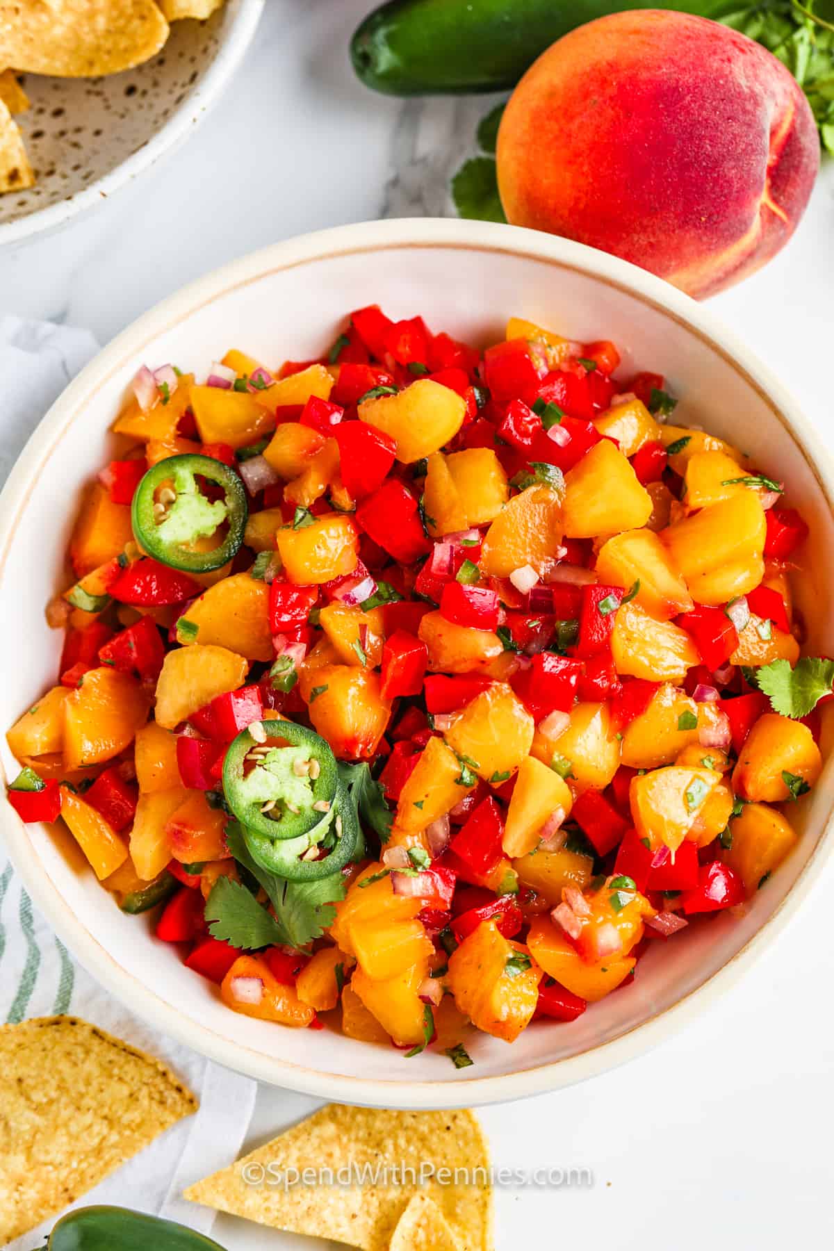 Peach salsa is an easy to make condiment that is sure to spruce up all kinds of dishes. Pork, salmon, chicken, and even tacos all taste delicious with this as an extra topping. And it is so easy to make this recipe, simply dice the peaches, add some lime juice, red pepper, onion, and jalapeno too and serve. So quick and easy! #peachsalsa #peachsalsarecipe #salsawithpeaches #spendwithpennies Peach Salsa in a bowl