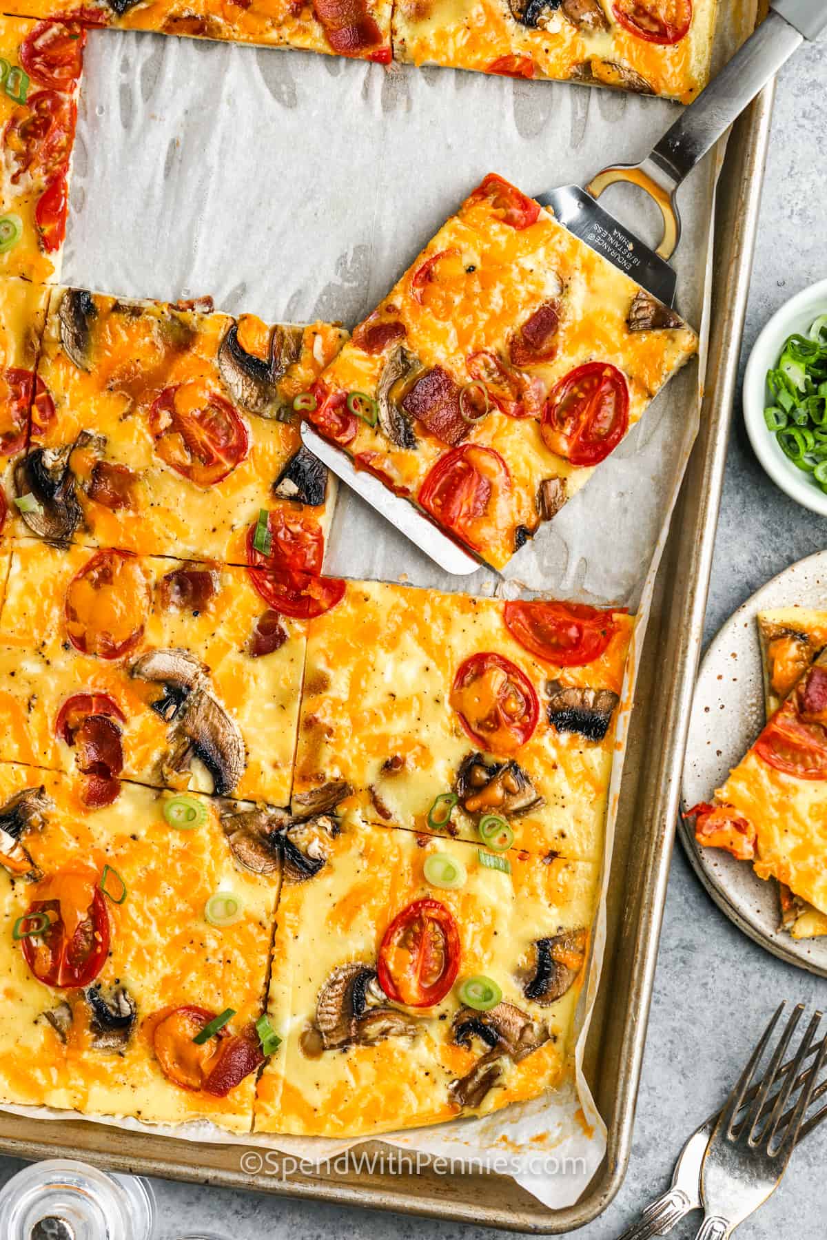 Sheet pan eggs make breakfast time easy! Let the oven do all the work with this simple baked eggs recipe. No need to make multiple portions of scrambled eggs in the morning, just cook one batch and reheat it all week! Sheet pan eggs are the best for busy mornings and big families since so many portions can be made at once. #sheetpaneggs #forbreakfastsandwiches #spendwithpennies #bakedeggsrecipe sliced Sheet Pan Eggs in the pan