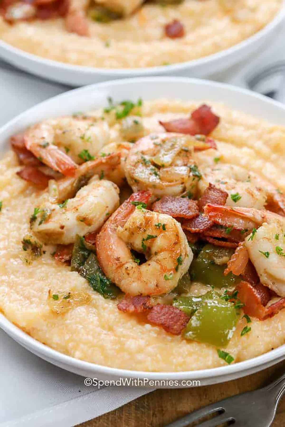These cheesy shrimp and grits are a comfort food classic from the south, and couldn't be easier to make. The combination of buttery grits, bacon, peppers, and shrimp makes a delicious mouth-watering dish that’s loved by all! #shrimpandgrits #southern #recipe #grits #spendwithpennies plated Shrimp and Grits