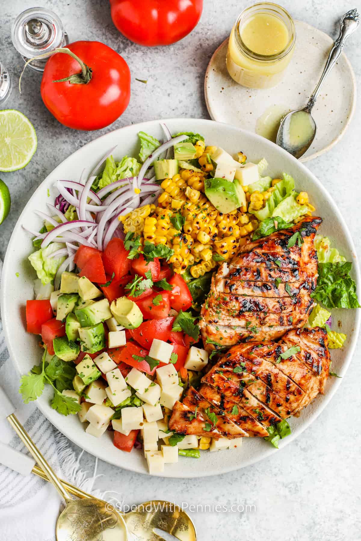 This grilled chicken salad is so easy to make and packed full of healthy protein and vegetables. Juicy and tender chicken breasts are seasoned with BBQ sauce and then grilled to perfection on the BBQ. Chicken is then ready for topping on a salad of romaine lettuce, corn kernels, cheese, and a light dressing. This is almost like a Cobb salad but with an extra punch of protein. #grilledchickensalad #grilledchickensaladrecipe #chickensalad #spendwithpennies top view of plated Grilled Chicken Salad