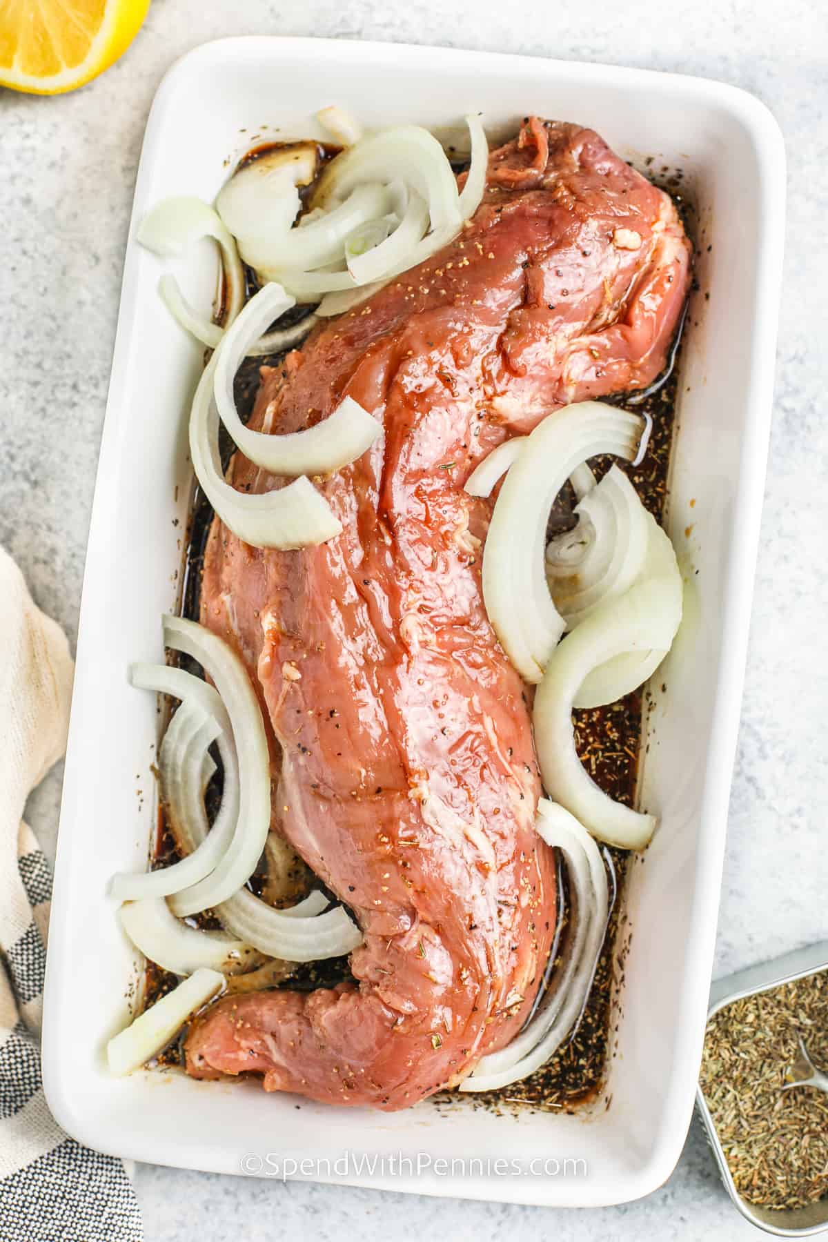 Grilled pork tenderloin is a delicious and nutritious option for a satisfying meal. The tenderloin is cooked on the grill until it's perfectly done, creating meat that is juicy and bursting with flavor. Its smoky and savory taste makes grilled pork tenderloin a crowd-pleaser at barbecues or family get-togethers. Once you try it, you'll be left wanting more of this tasty and satisfying dish! #grilledporktenderloin #porktenderloin #recipe #spendwithpennies pork and onions with sauce in a dish to make Grilled Pork Tenderloin