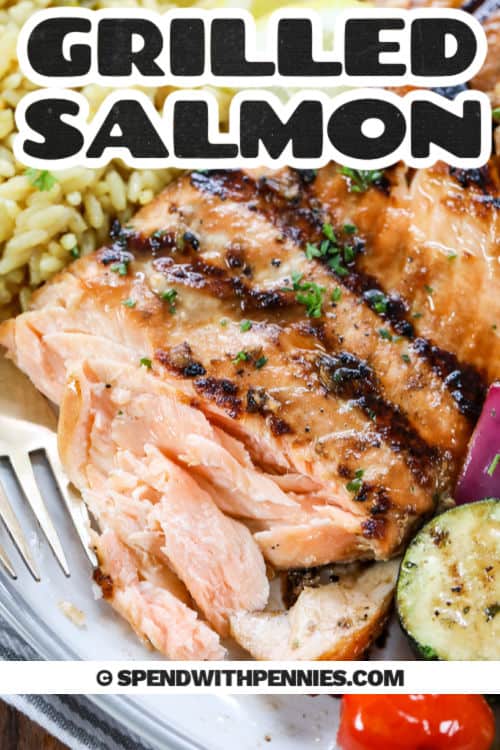 Cook this easy recipe for grilled salmon in no time. It's so simple to marinate a tender skin-on salmon fillet and grill it with foil or on a cedar plank. Serve it alone or with a simple lemon sauce. BBQ smoke adds that extra delicious flavor. With this healthy recipe, there is no need to worry about the calories, either! #grilledsalmon #recipe #healthy #spendwithpennies plated Easy Grilled Salmon with vegetables and a title