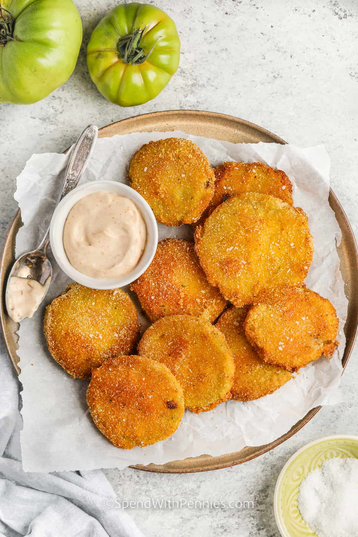 This southern style dish of fried green tomatoes is the perfect addition to the summer menu. The light crispy coating of these tomatoes will be so hard to resist. And they are so easy to make. Just dredge them in a cornmeal mixture and then lightly friy in a skillet on the stove. #friedgreentomatoes #friedgreentomatoesrecipe #sidedish #spendwithpennies plated Fried Green Tomatoes with dip
