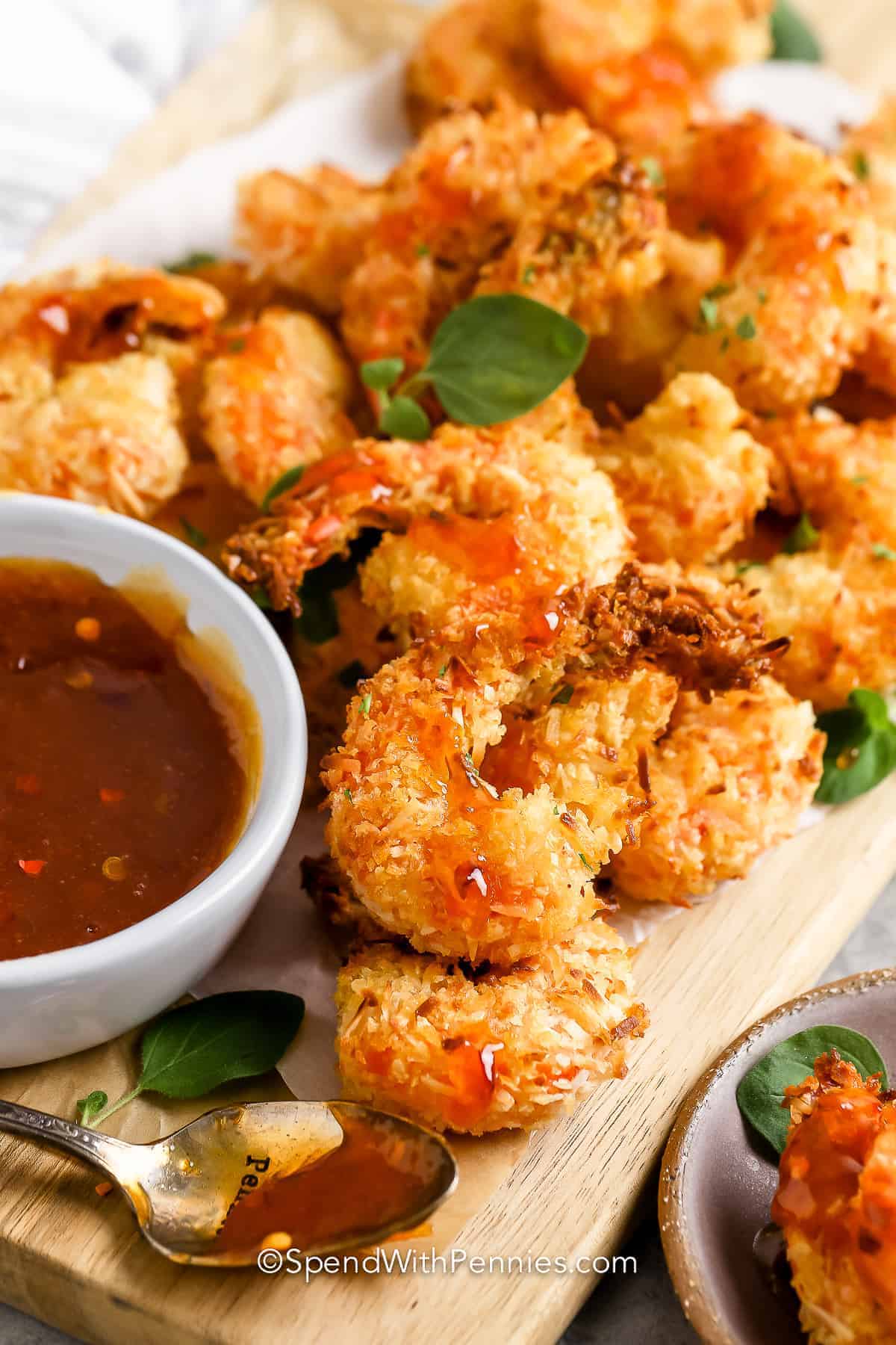 It won't take long to have an appetizer that guests will love with this easy coconut shrimp recipe. Jumbo shrimp are breaded in coconut and flour and then baked in the oven until they are a golden brown crispy creation. These are the best served with a sweet cocktail sauce. #coconutshrimp #coconutshrimprecipe #easycoconutshrimp #spendwithpennies Coconut Shrimp with dip