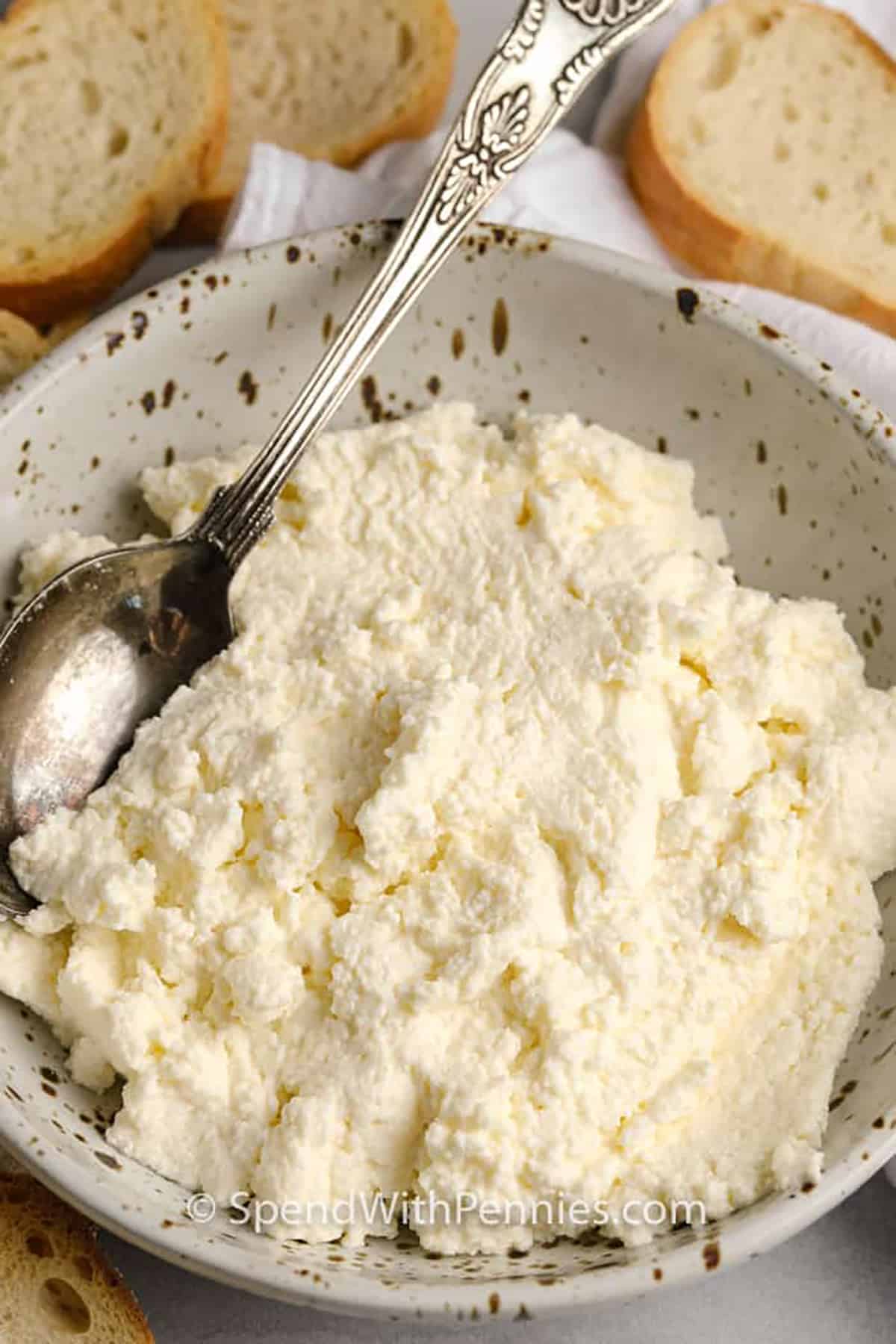 Homemade ricotta cheese is soft, creamy, and surprisingly easy to make with just milk, cream, and vinegar. No fancy tools required—just heat, stir, and let it rest before draining through cheesecloth. The result is a rich and velvety cheese that tastes amazing in everything from lasagna to lemon desserts. Once you try this homemade version, store-bought won’t compare! #spendwithpennies bowl of Ricotta Cheese