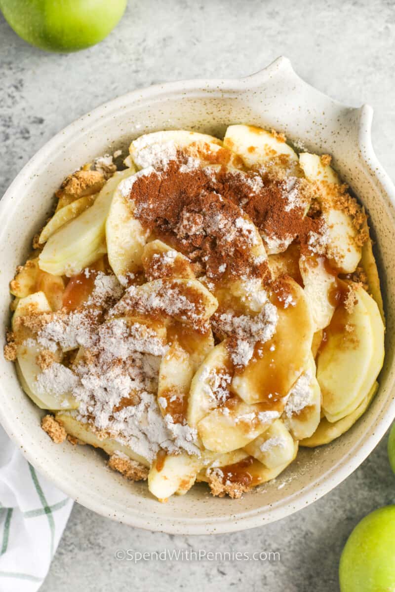Whip up a cozy apple cobbler that everyone in the family will adore. Crafted with homemade apple pie filling and topped with a sweet, buttery biscuit layer, this treat is crispy, delicious, and takes just 15 minutes to prep. Serve it with a scoop of ice cream or a dollop of whipped topping for a dessert to remember. #applecobbler #dessert #homemade #spendwithpennies Ingredients to make the apple cobbler filling in a bowl