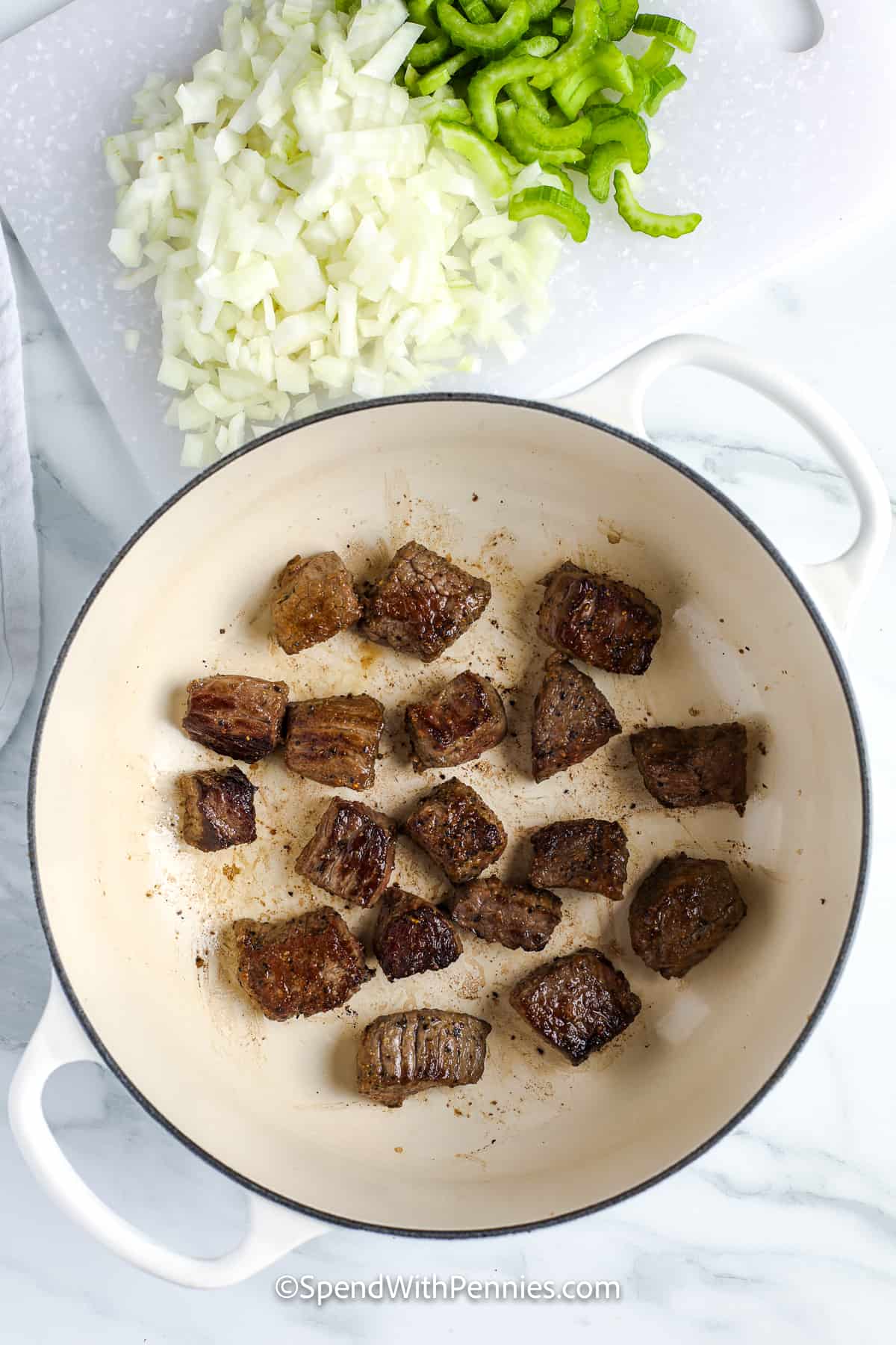 This beef and noodles recipe features tender beef, egg noodles, and delicious gravy for the ultimate family meal. The beef is browned, then cooked with onions, celery, broth, and spices until savory and rich. Spoon it over noodles for a dish that warms from the inside out. With its simple prep and classic flavor, this recipe is easy to love and perfect to serve any night of the week. Add a side of broccoli for freshness. #spendwithpennies cooked beef cubes in a pot