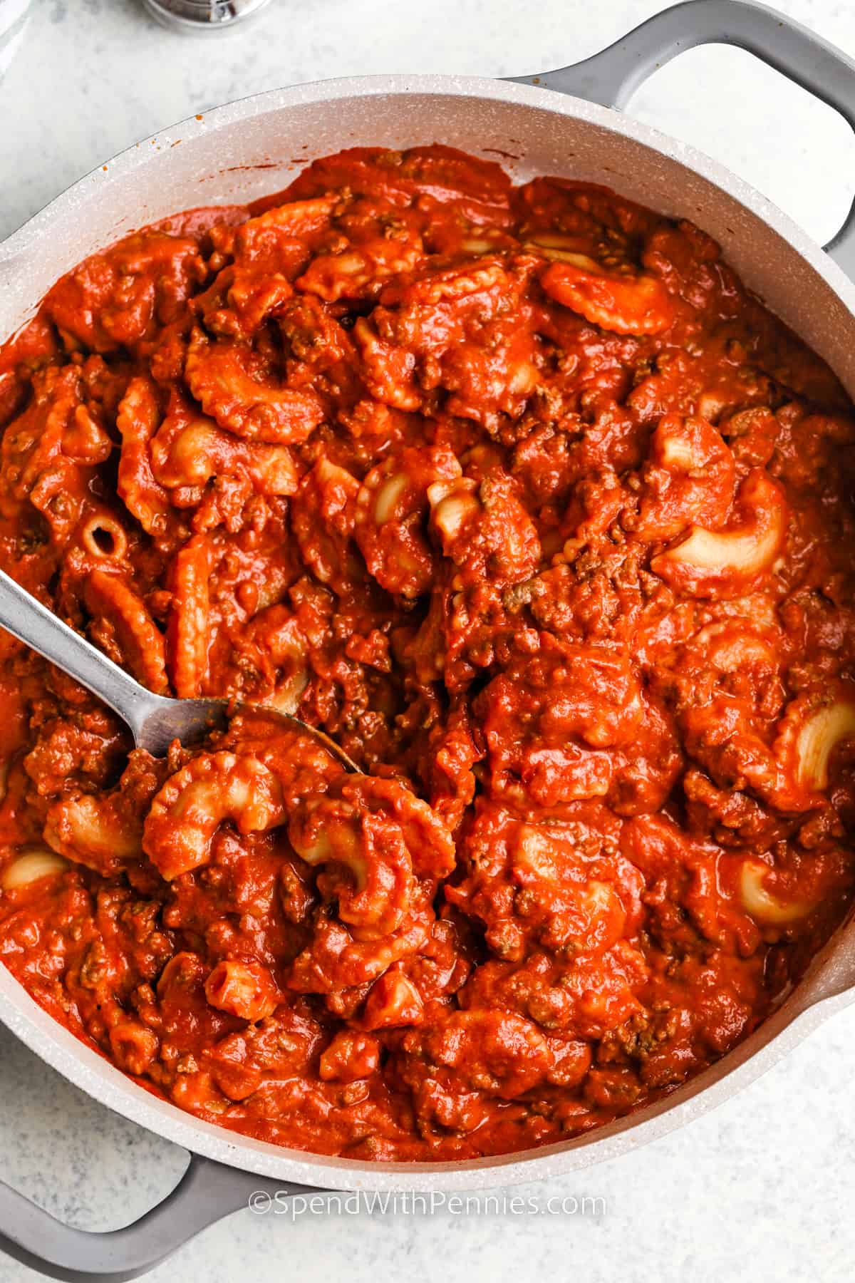 Homemade beefaroni is one of the best comfort meals you can make from scratch. It’s a family favorite with tender pasta, savory beef, creamy tomato sauce, and a cheesy topping. Everything cooks together in one pot, making it a simple stovetop dinner that’s both hearty and delicious. It’s perfect for busy nights or anytime you’re craving old fashioned flavor. #spendwithpennies cooked Homemade Beefaroni in the pot
