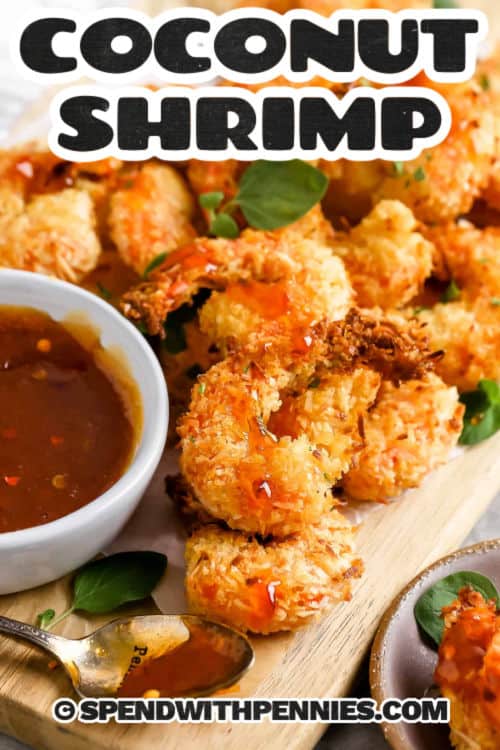 It won't take long to have an appetizer that guests will love with this easy coconut shrimp recipe. Jumbo shrimp are breaded in coconut and flour and then baked in the oven until they are a golden brown crispy creation. These are the best served with a sweet cocktail sauce. #coconutshrimp #coconutshrimprecipe #easycoconutshrimp #spendwithpennies Coconut Shrimp with sauce and a title