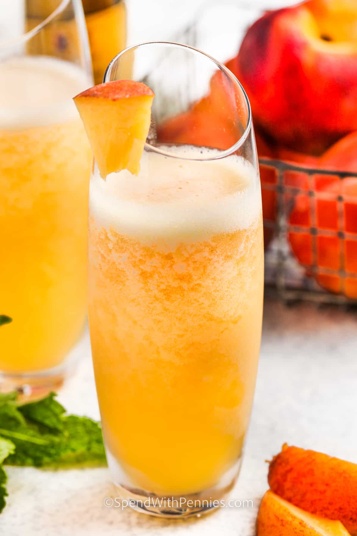 Peach Bellinis are super fresh and sweet, making them a big hit at summer parties and backyard barbecues! These cocktails are super easy to make with only 3 ingredients blended into a frozen treat. You can use iced wine or Prosecco to start a new tradition of sipping this tasty cocktail by the poolside. #peachbellinis #peachbellinirecipe #frozenpeachbellinis #spendwithpennies homemade Peach Bellini