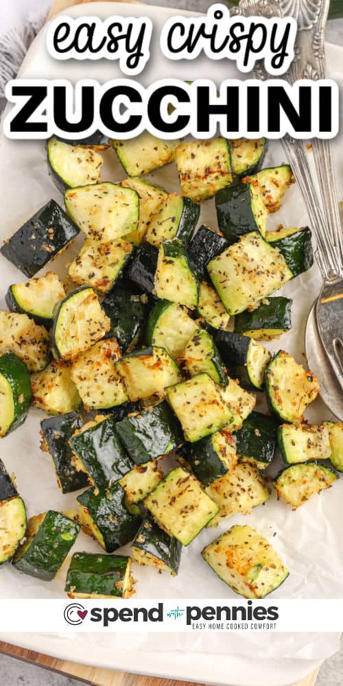 Indulge in a healthy and delicious dish with air fryer zucchini. Diced zucchini pieces are seasoned, air fried until they turn crispy, and served on their own or with dippers. They make for a delightful snack or a satisfying side dish. With its quick cooking time and minimal oil usage, air fryer zucchini is a guilt-free snack or side dish! #airfryerzucchini #zucchini #snack #sidedish #spendwithpennies Air Fryer Zucchini with a fork and spoon with writing