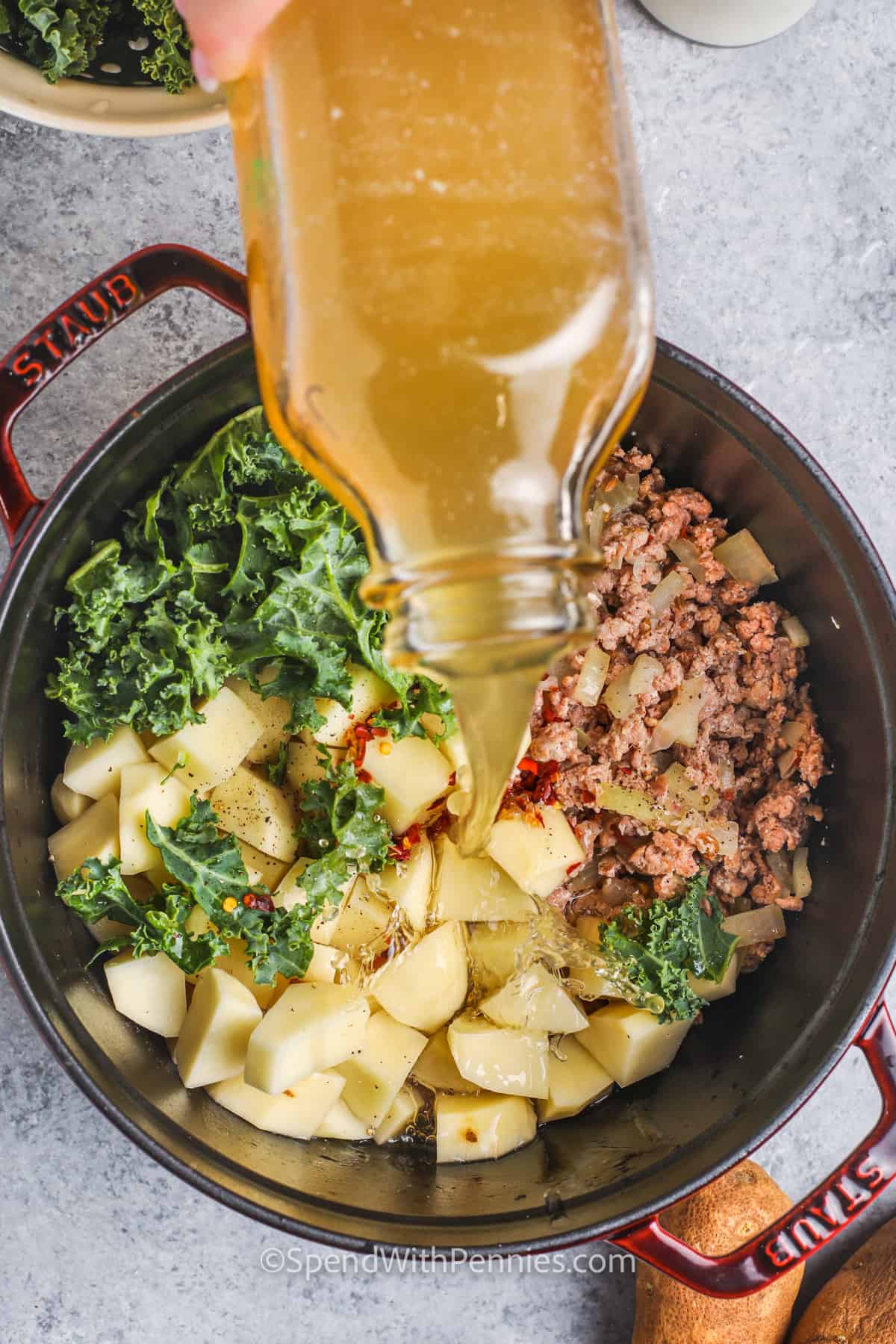 adding broth to ingredients to make Zuppa Toscana