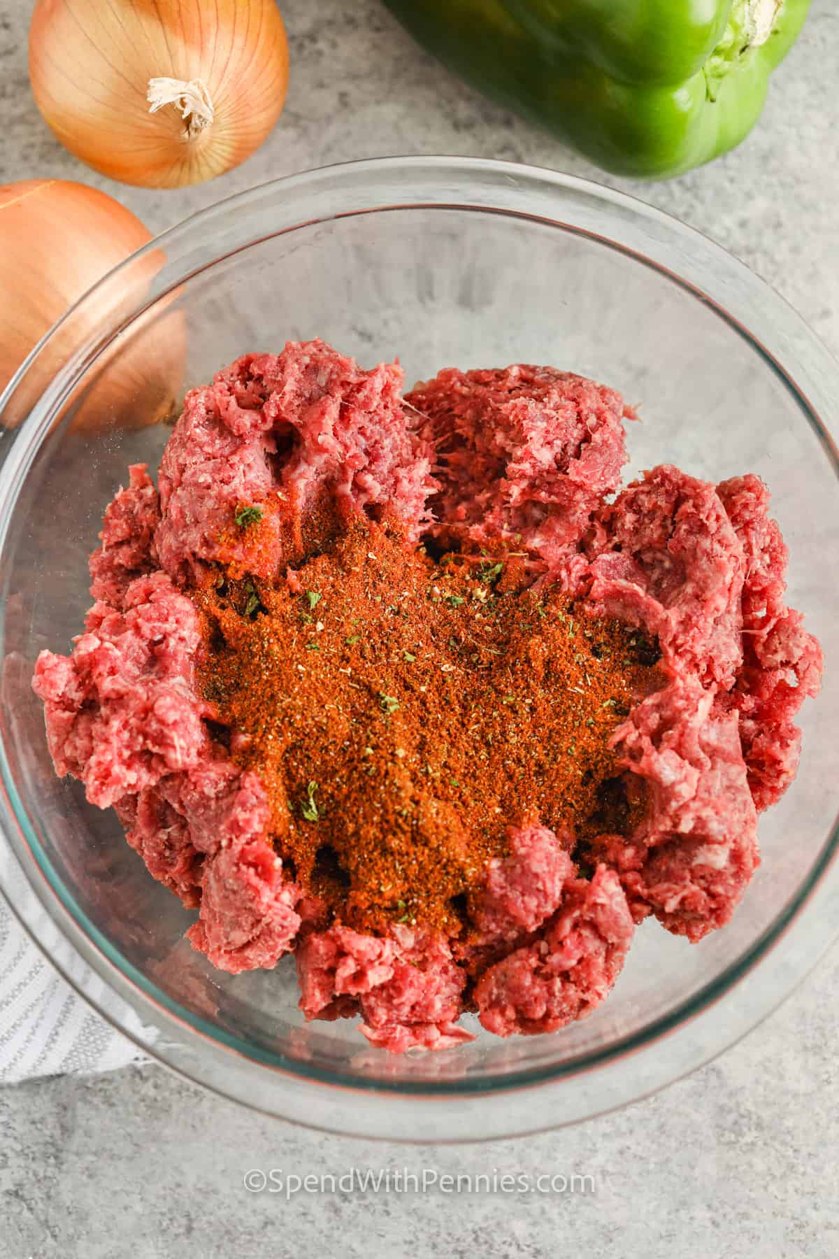 Easy crockpot chili is packed with protein and fiber thanks to lean beef and kidney beans, making it both filling and nutritious. A flavorful seasoning blend with smoked paprika, cumin, and oregano adds warmth and depth, while diced onions, garlic, and optional bell peppers bring freshness. Letting it cook all day in the crockpot enhances the flavor, making it even better the next day. #spendwithpennies adding spices to beef to make Easy Crock Pot Chili Recipe