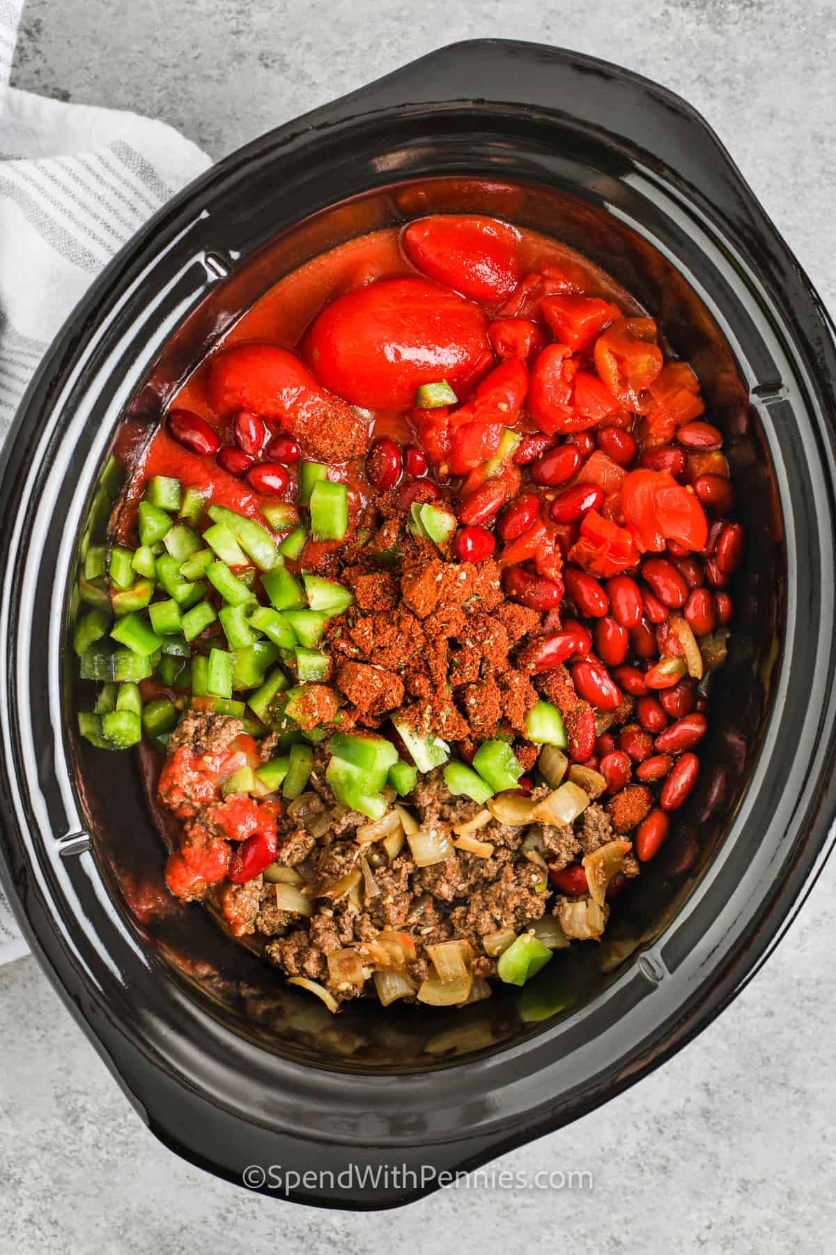 For fantastic Crock Pot chili, check out this easy recipe. You can customize it by using chicken or turkey instead of ground beef for a white chili variation. Or go for a vegetarian version with three types of beans and healthy green veggies. The rich and savory sauce in this recipe is a perfect match for various ingredients! #spendwithpennies Easy Crock Pot Chili Recipe ingredients in a crock pot
