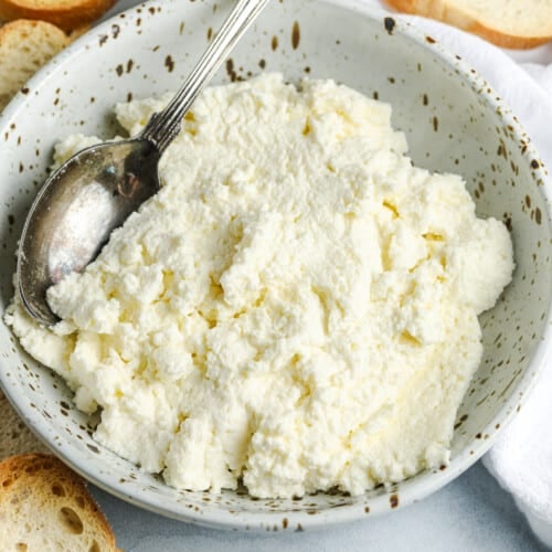 a bowl of homemade ricotta cheese next to crostini