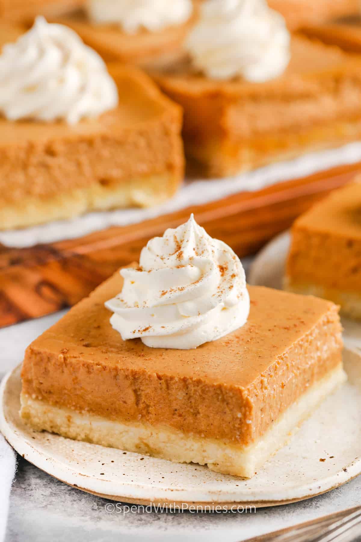 Indulge in this perfect and easy pumpkin pie bars recipe, combining the creamy goodness of cheesecake-like filling with the warm spice of pumpkin. The shortcake crust adds an extra layer of flavor and texture. Add a pecan topping to provide the perfect crunch. Try this delectable cake for a taste of fall in every bite! #pumpkinpiebars #dessert #easy #spendwithpennies Pumpkin Pie Bars on plates