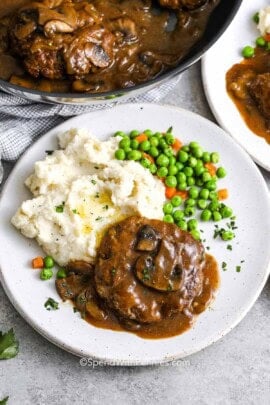 Salisbury Steak on a plate with mashed potatoes and peas