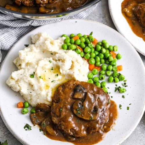 Salisbury Steak on a plate with mashed potatoes and peas