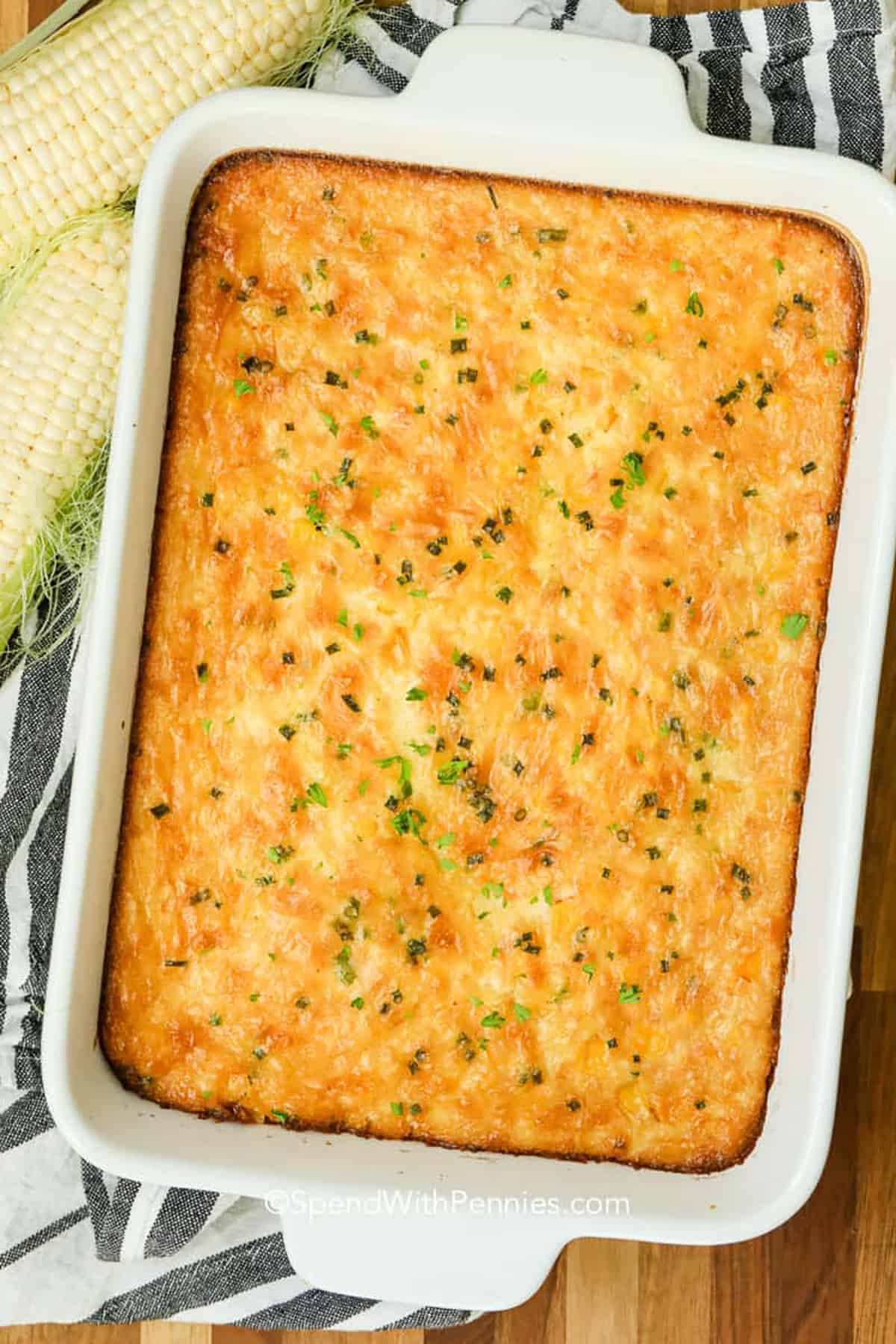 Corn pudding is the perfect mix of creamy and sweet, a southern-inspired side dish that everyone will love. This easy recipe uses creamed corn, eggs, and butter for a rich, custardy texture that melts in your mouth. It’s simple to make and pairs beautifully with roasted meats or holiday entrees. A spoonful of this comfort food will bring warmth to any meal. #spendwithpennies Corn pudding in a white casserole dish