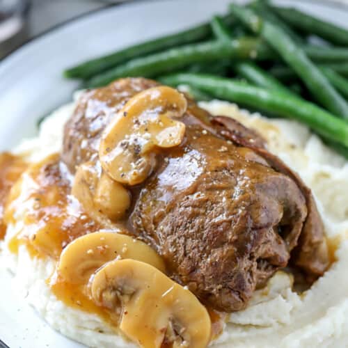 beef rouladen on a white plate with mashed potatoes and gravy