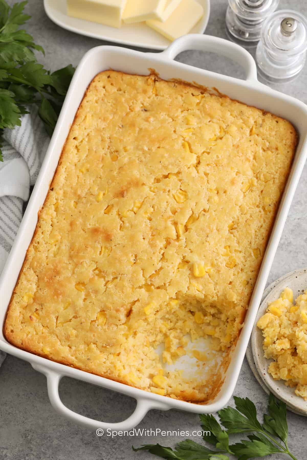 This easy corn casserole recipe is a southern comfort food staple. Made with Jiffy Corn Muffin Mix, fresh or frozen corn, and creamed corn, this recipe can easily be made ahead and leftovers freeze well! It comes out golden, moist, and buttery every time, so make a double batch and enjoy it all year round! #corncasserole #thanksgiving #christmas #spendwithpennies baked corn casserole in a white baking dish