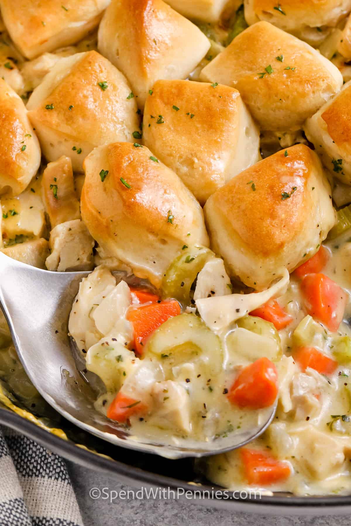 Easy chicken and biscuits are a delicious way to turn leftover or rotisserie chicken into a completely new meal. A creamy chicken and vegetable filling is topped with refrigerated biscuit dough and baked until the sauce bubbles and the biscuits become fluffy and golden. It has the cozy flavors of chicken pot pie with an easy biscuit topping and just 20 minutes of prep. Add this simple comfort food recipe to your weeknight dinner board. #spendwithpennies taking a spoonful of Chicken and Biscuits