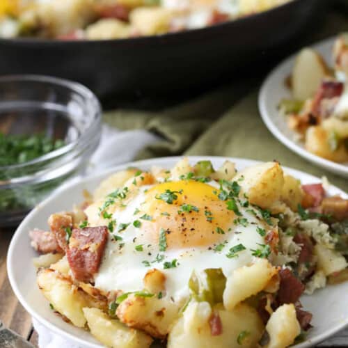 Plates of corned beef hash on a table, with a skillet.