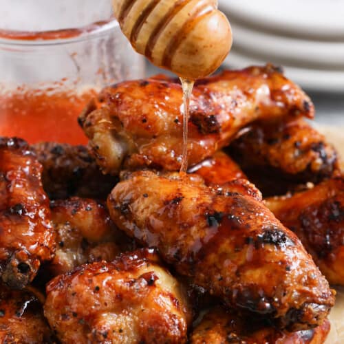 pouring hot honey over plated Honey Hot Wings