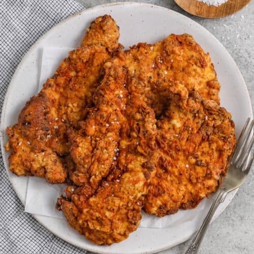 Crispy Fried Chicken Breast on a plate with a fork and salt