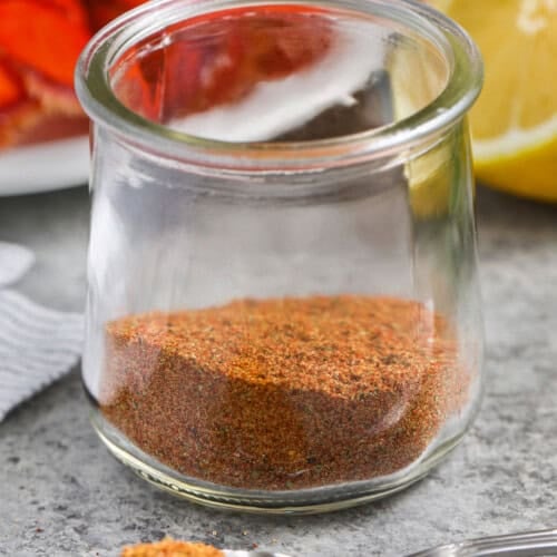 Old Bay Seasoning in a jar with lobster and lemon in the back