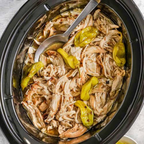 Crock Pot Mississippi Chicken in a slow cooker with a seruing spoon