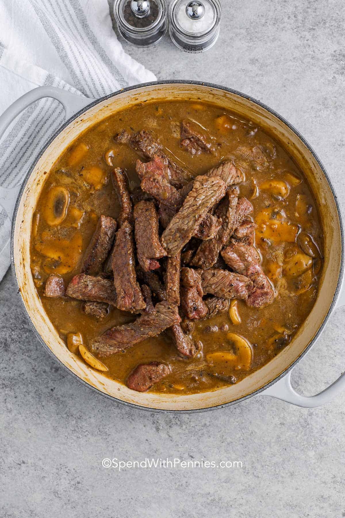 steak on top of beef stroganoff sauce in a pot