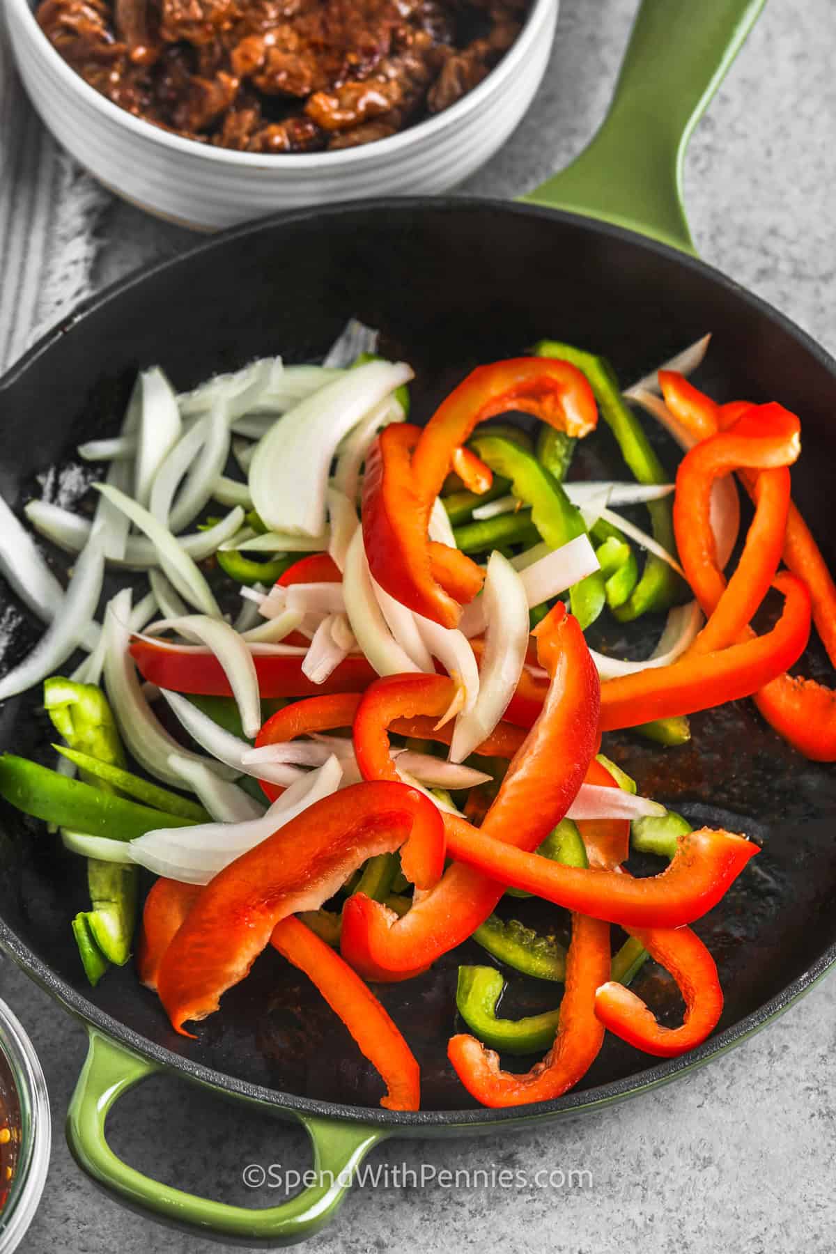 Pepper steak and rice is a comforting dinner made with saucy beef, bell peppers, and onions in a savory garlic ginger sauce. The vegetables stay tender-crisp, the beef cooks quickly, and the sauce thickens right in the skillet. It is a great recipe for meal prep since leftovers reheat well for lunch or another easy dinner later in the week. #spendwithpennies veggies in a pan for pepper steak