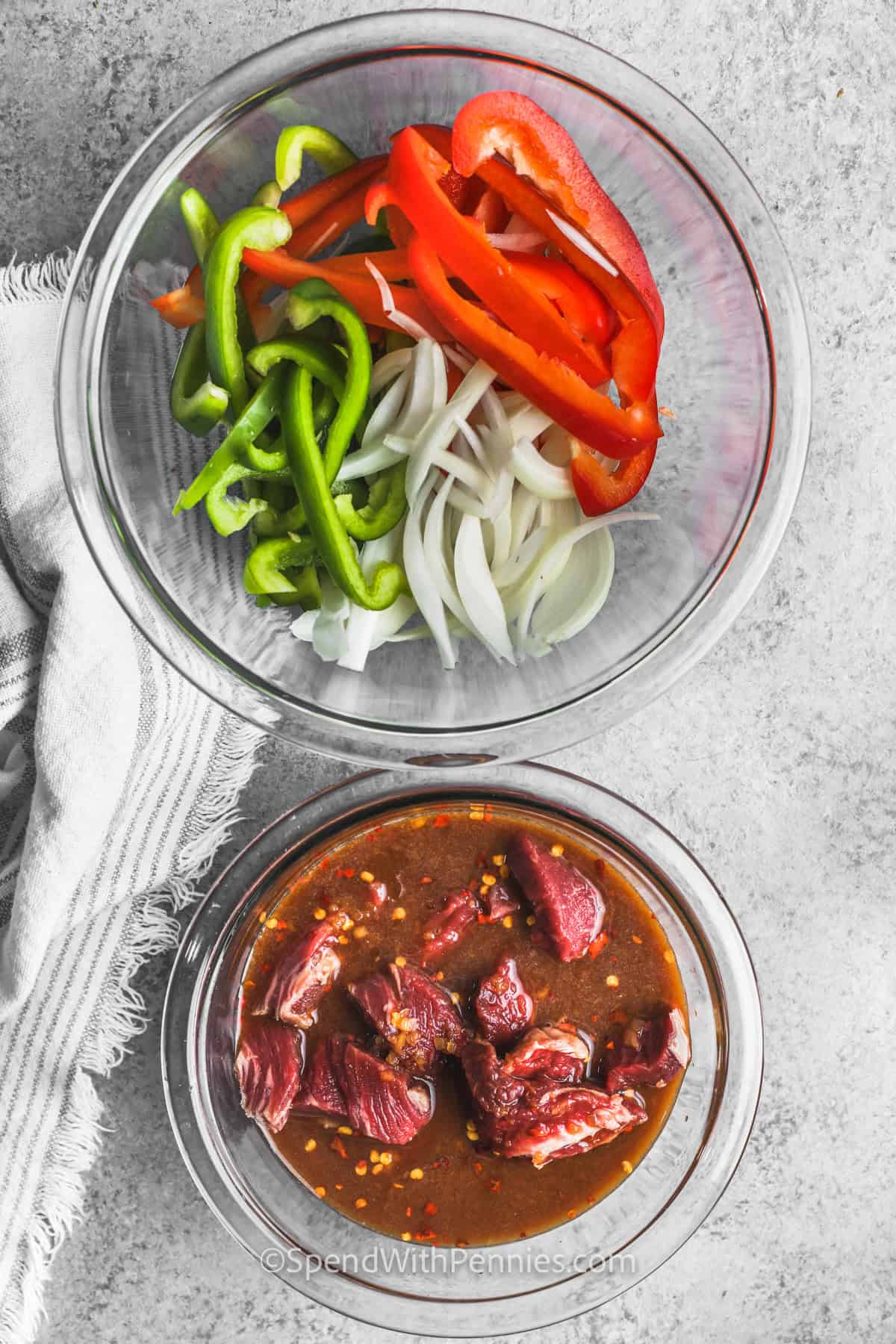 marinating steak in a bowl with a bowl of veggies to make Easy Pepper Steak