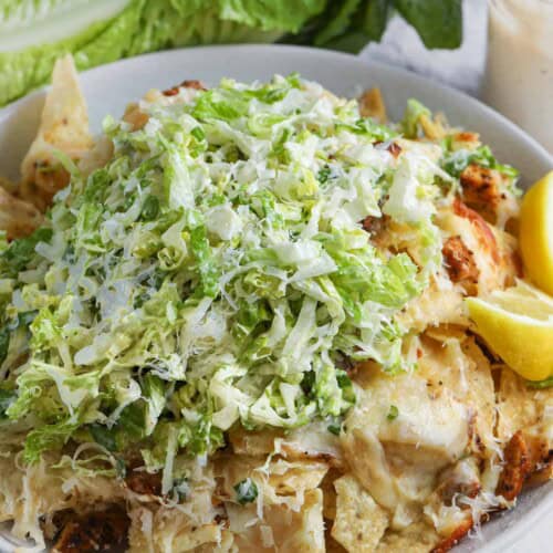A bowl of nachos topped with shredded salad