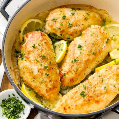 a dutch oven with lemon pepper chicken breasts and slices of lemon
