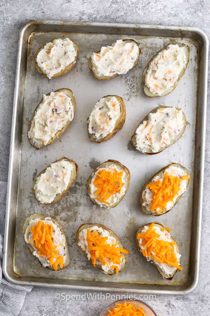 adding cheese on top of potatoes with filling to make Twice Baked Potatoes