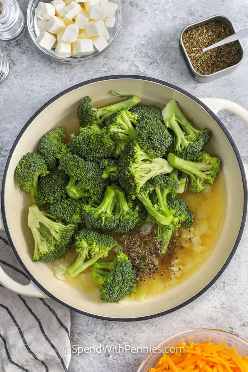 Adding broccoli florets to sauteed onion and chicken broth to make broccoli cheddar soup.