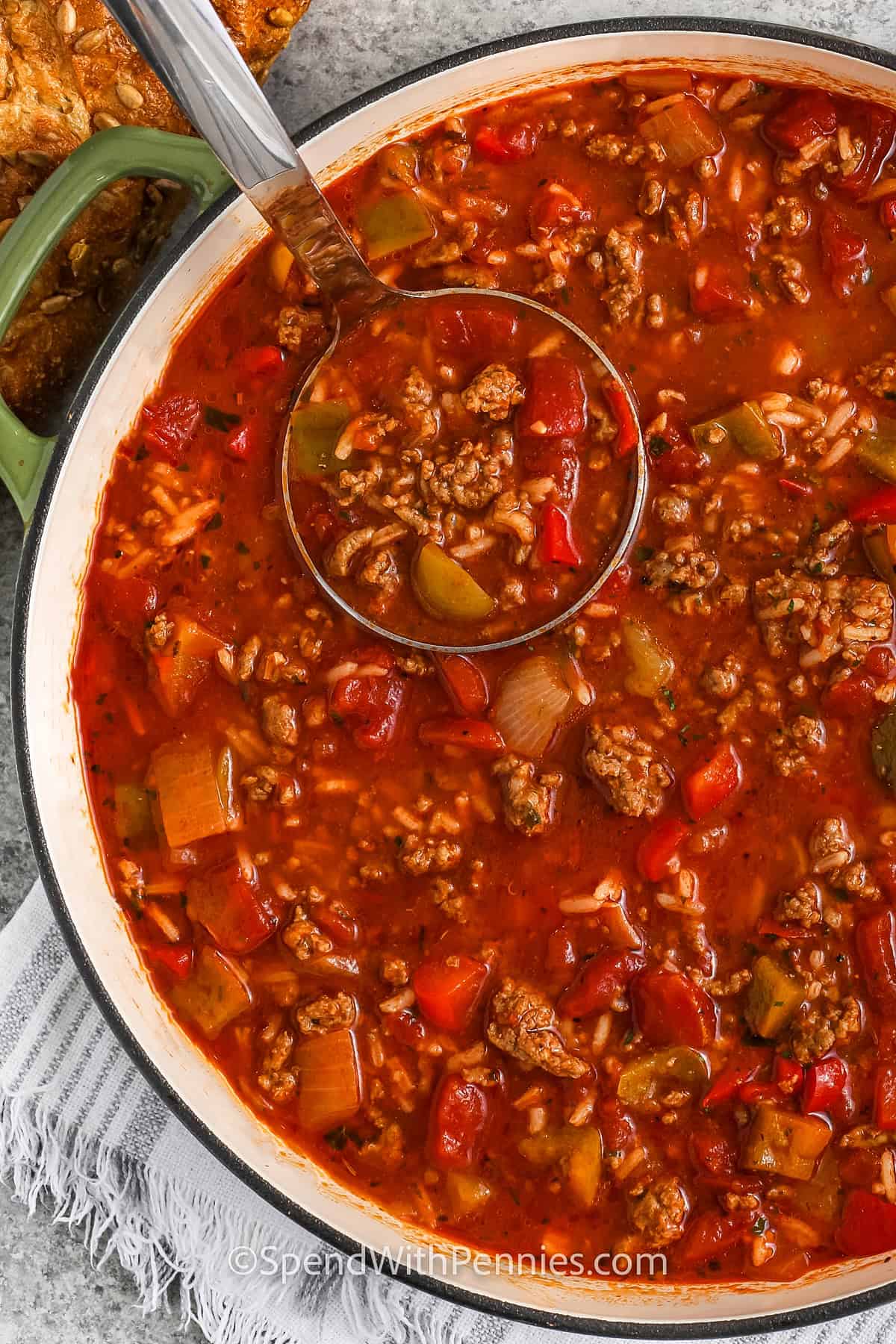 Stuffed pepper soup is a delicious twist on the classic dish, made into an easy-to-eat soup. This recipe uses ground beef, bell peppers, tomatoes, and rice to create a satisfying, well-rounded meal. It’s freezer-friendly, reheats well, and makes enough to feed the whole family. Add a sprinkle of cheese or a side of bread to complete this comforting dinner. #spendwithpennies taking a spoonfull of Stuffed Pepper Soup out of the pot