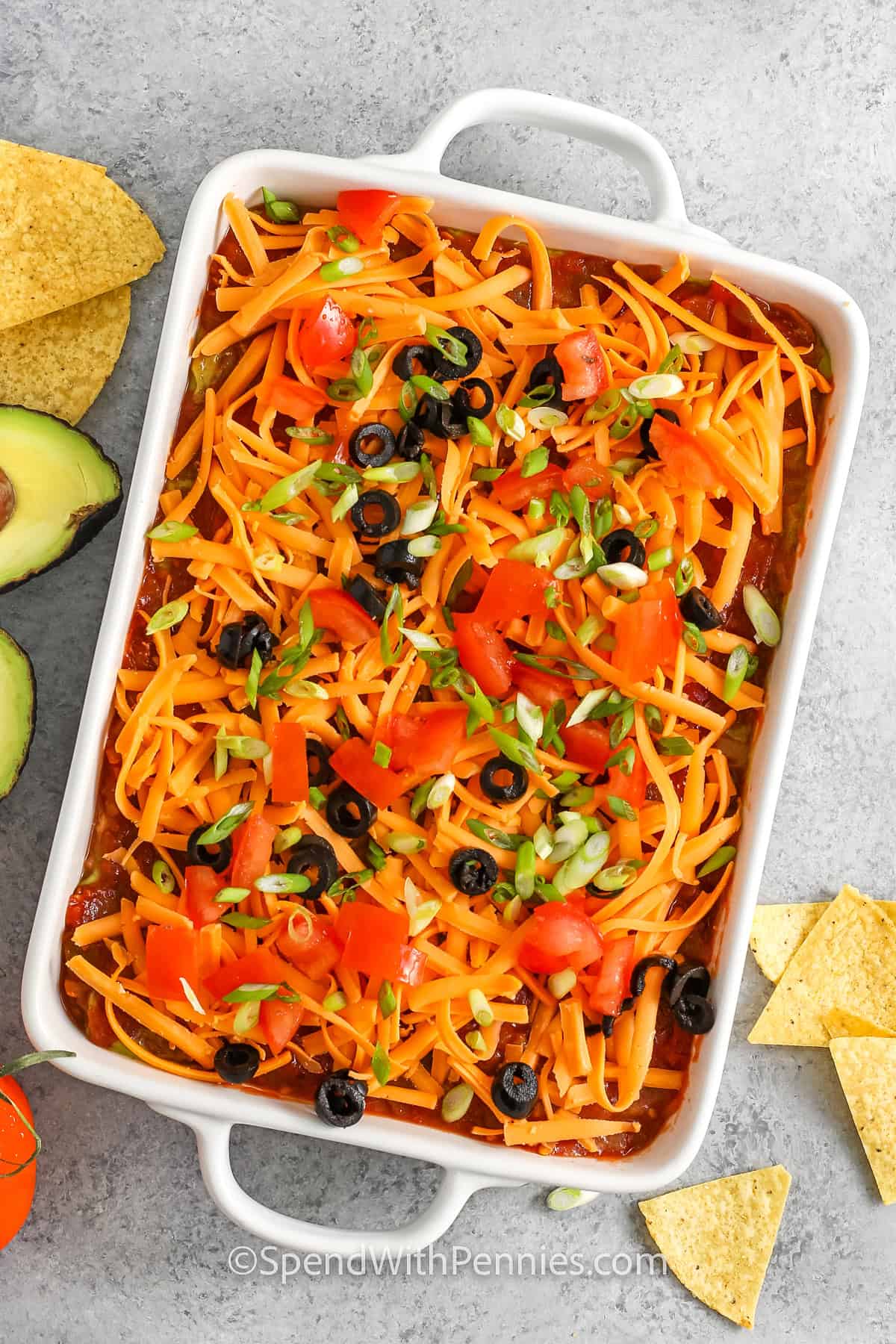 adding cheese and veggies to dish to make 7 Layer Dip